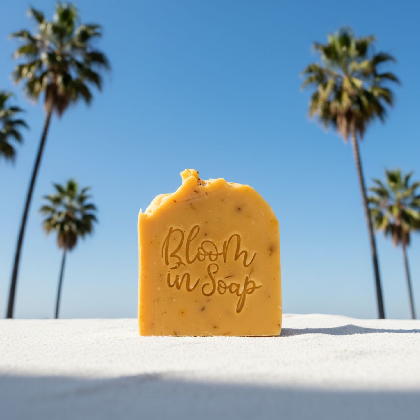 Bar of soap with 'Bloom in Soap' text against a beach backdrop with palm trees.