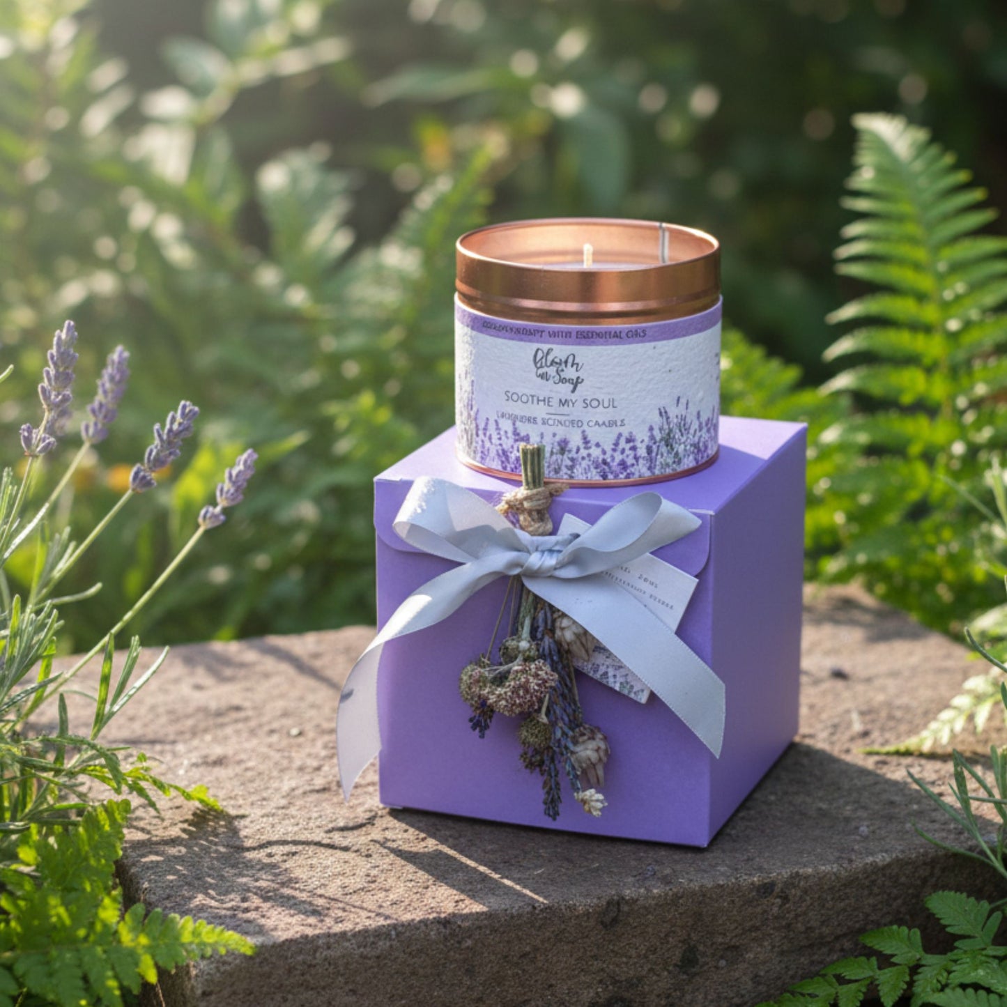 Candle in a purple box with lavender elements on a stone surface with greenery in the background