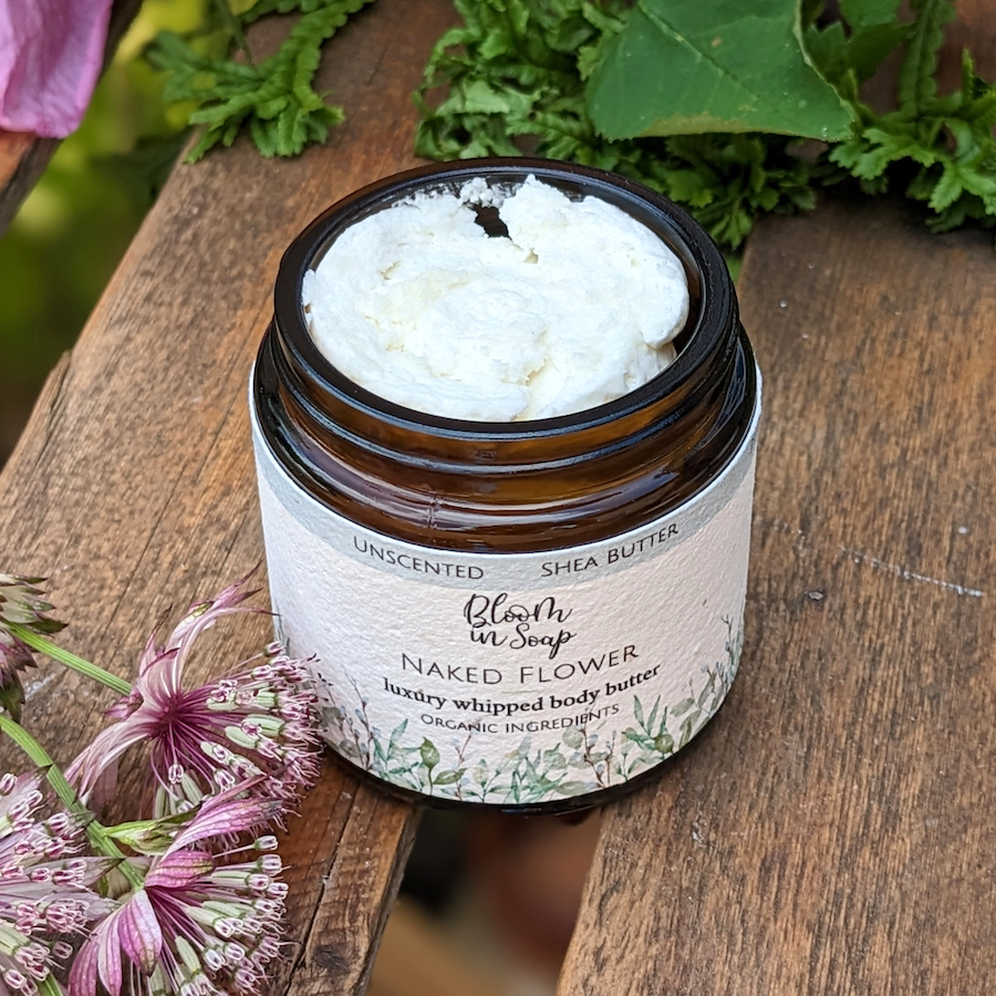 Naked Flower luxury body butter in a jar on a wooden tray