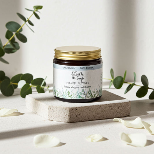 jar of body butter with petals and greenery in the background