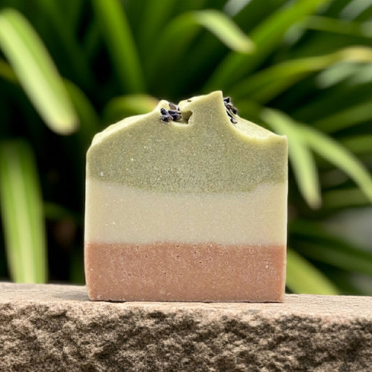 Natural salt soap sitting on a stone with greenery in the background