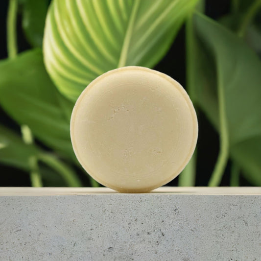 Delicate Flower Conditioning Shampoo Bar on a stone platform with greenery in the background