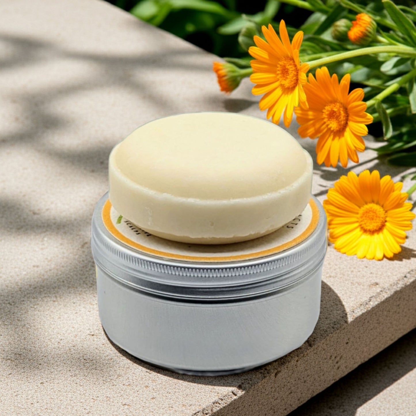 a shampoo bar sitting on top of a tin with calendula flowers in the background