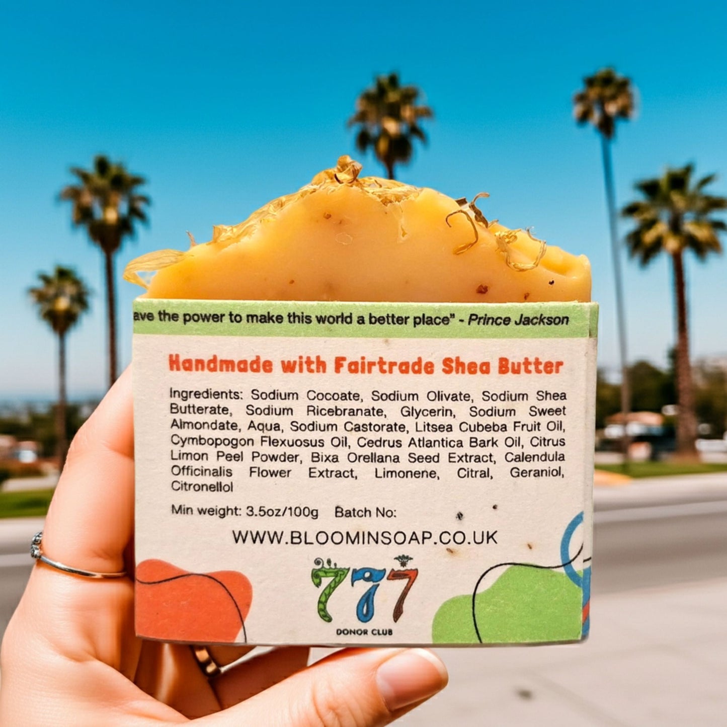 Handmade soap with a label held in front of palm trees