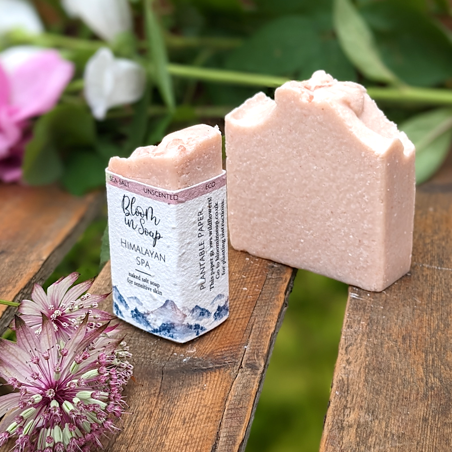 Pink clay and salt handmade soap on a wooden try with plants and leaves
