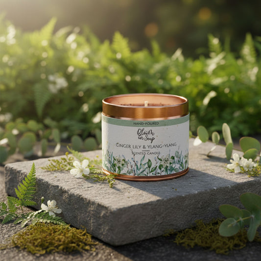 Candle with a copper lid on a stone surface surrounded by greenery
