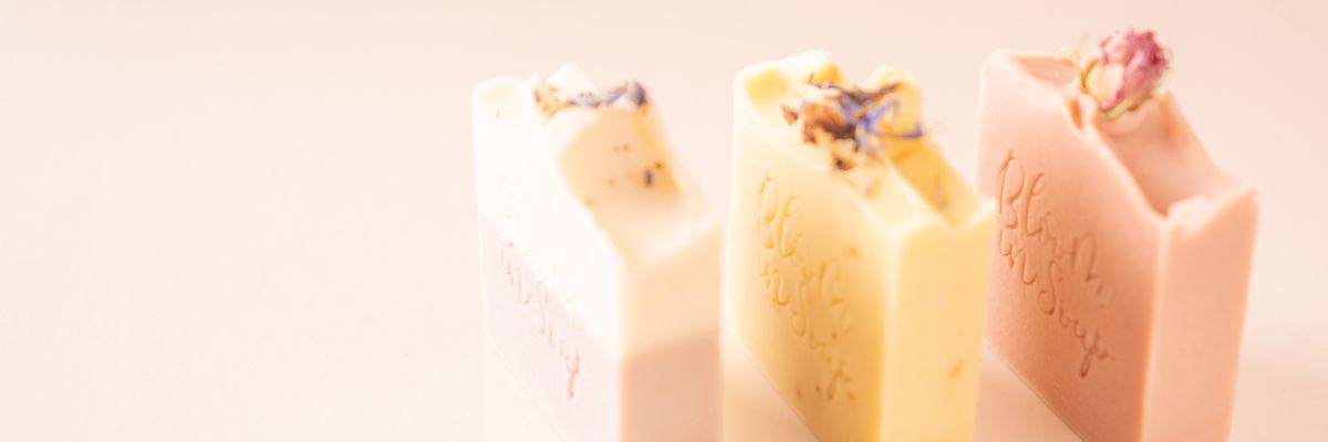 Natural soaps with botanical flowers on top and stamped with Bloom In Soap