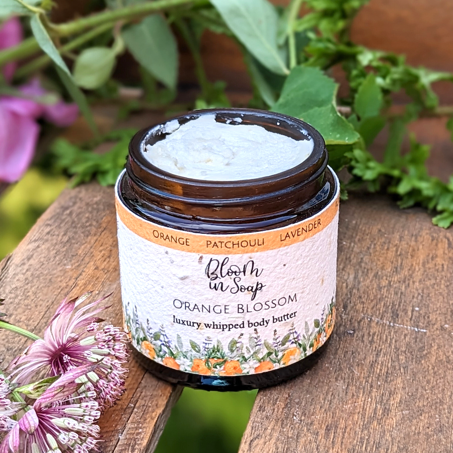 Orange Blossom luxury body butter in a jar on a wooden board