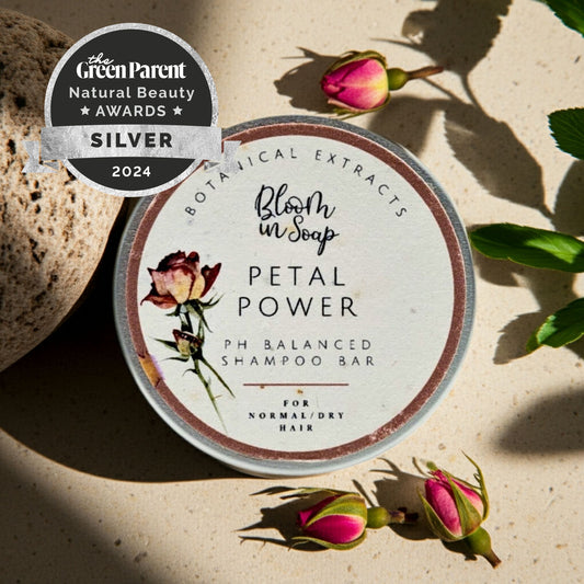 Shampoo bar with 'Petal Power' label surrounded by flowers on a textured surface, featuring the Green Parent Natural Beauty Awards silver badge.