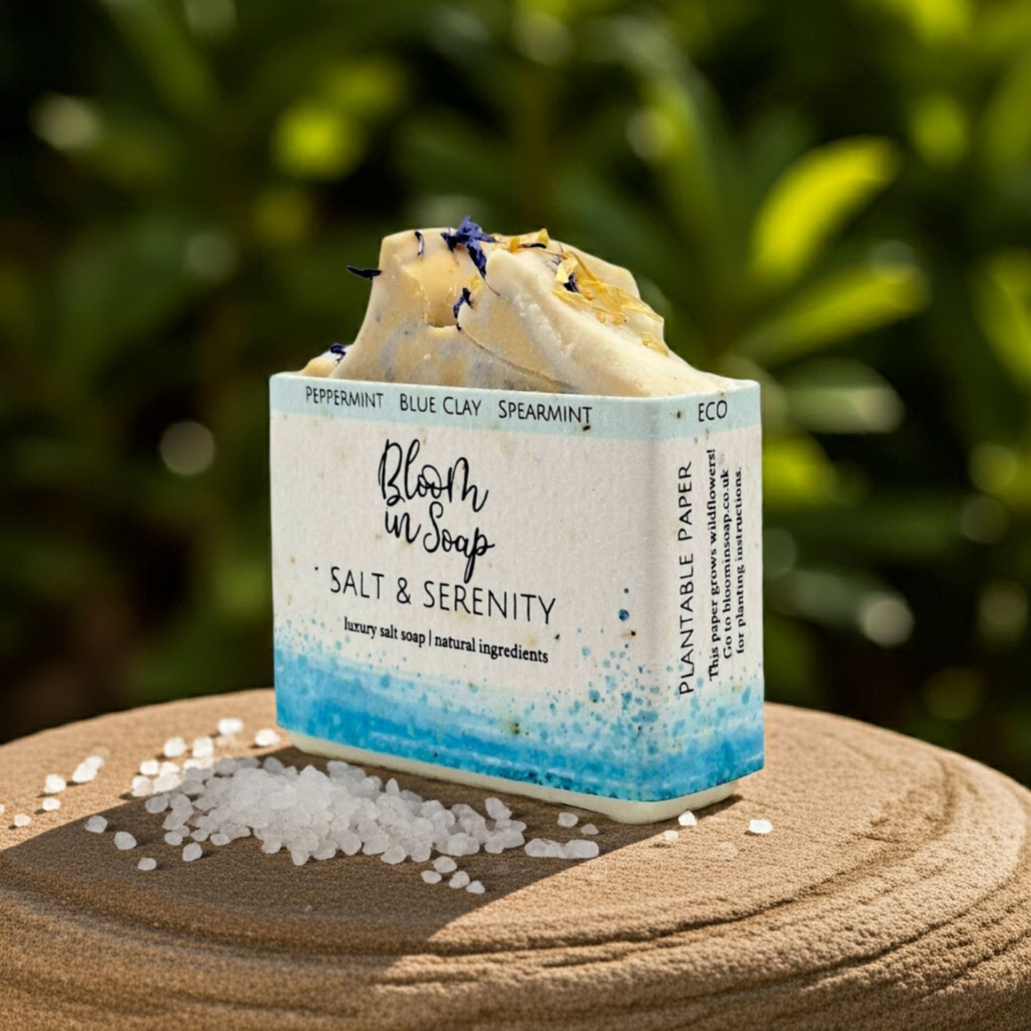 Bar of soap with a visible label on a sandy surface with a blurred green background