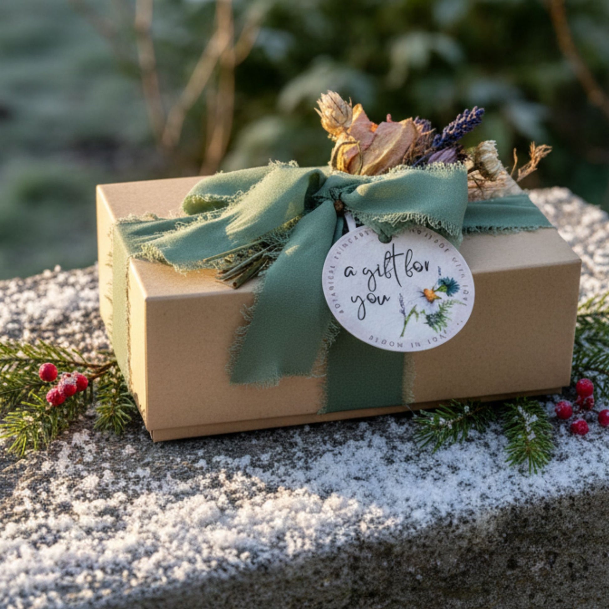Gift box with a green ribbon and decorative tag, set against a snowy outdoor background.
