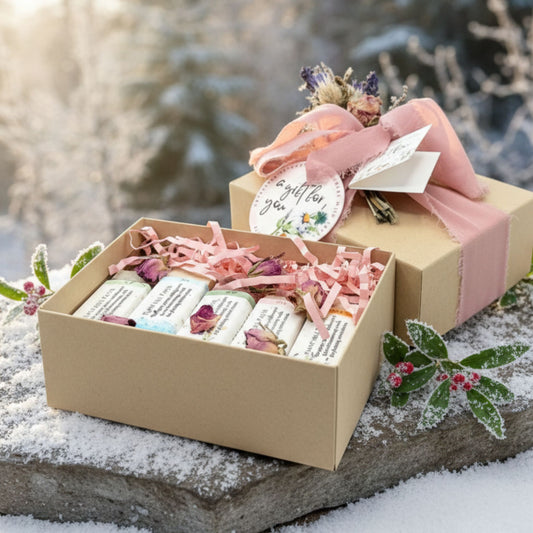 Gift box with 5 soap bars, ribbons, and a card on a snowy surface