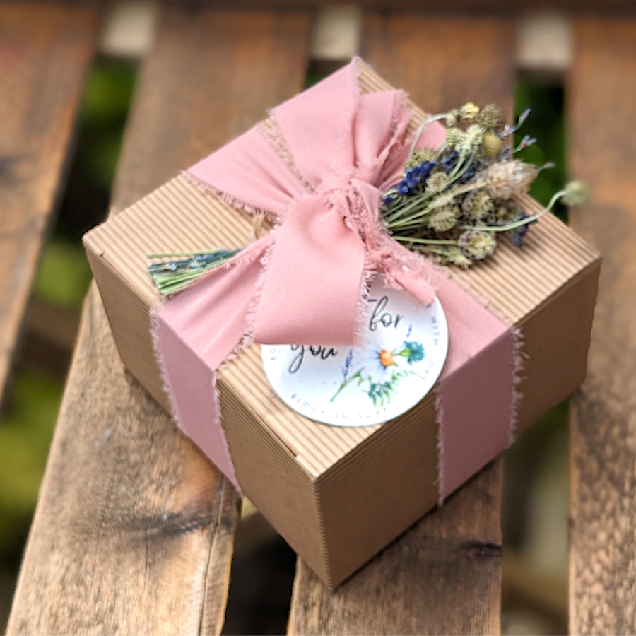 Gift box tied with pink ribbon and decorated with dried flowers