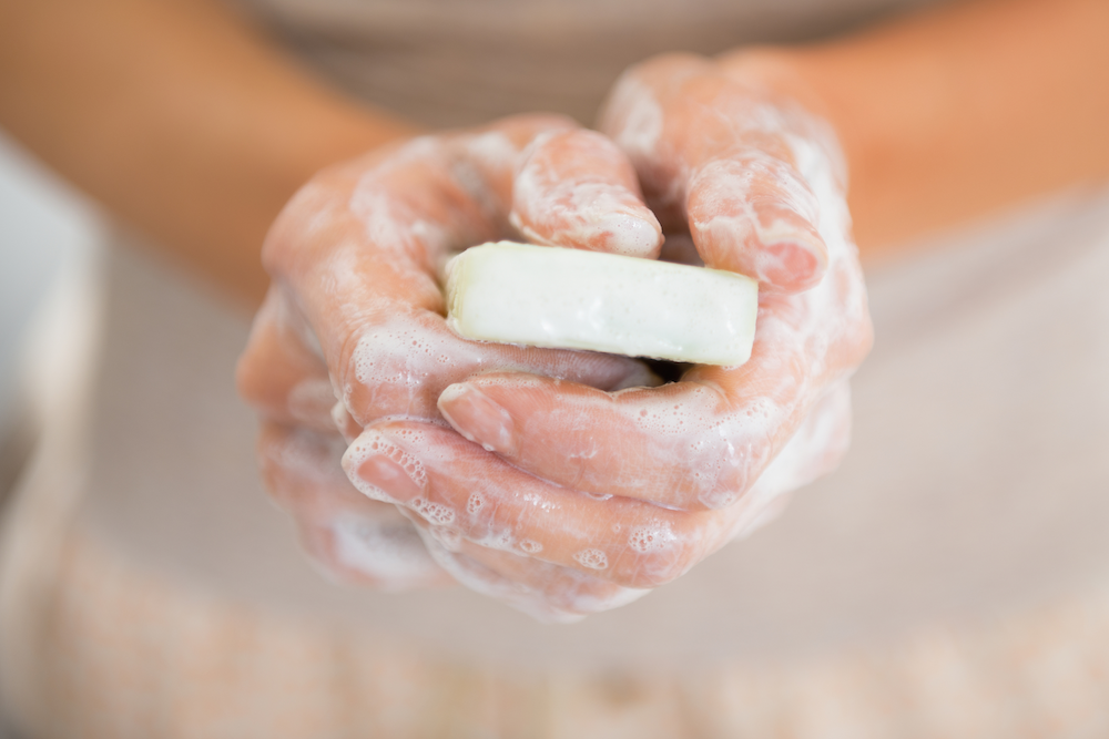 a woman washing her hands with a natural soap bar