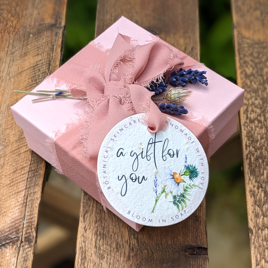 pink gift box tied with ribbon and decorated with flowers and a plantable gift tag