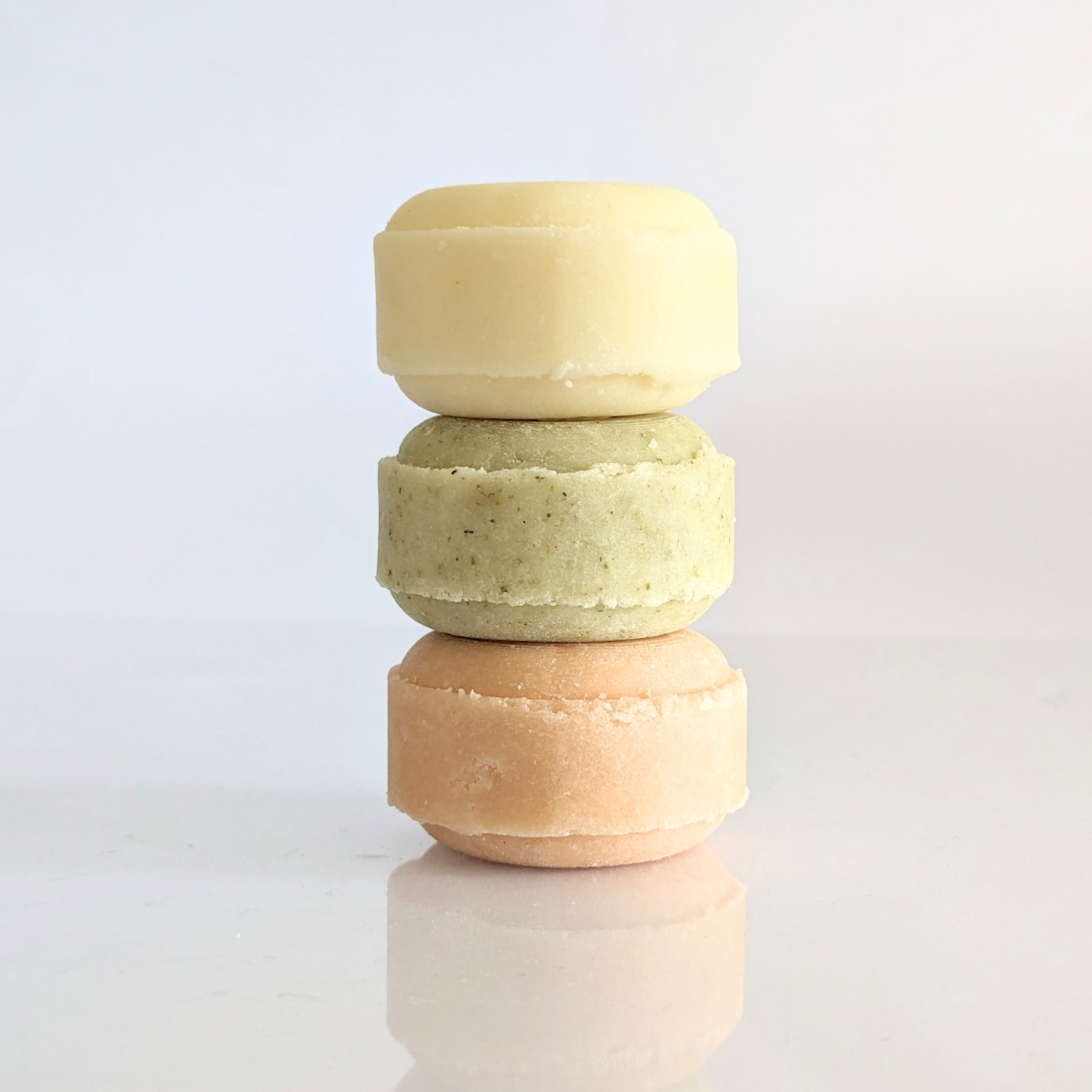 A stack of solid shampoo bars in yellow, green and pink